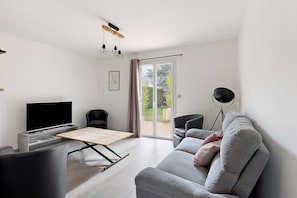 Een moderne woonkamer met een flatscreen televisie, een bank, een salontafel en een eettafel.