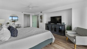 A modern bedroom with a large bed, a TV, and a seating area. - Forest Dunes 1802- Ocean View 3BR/2.5BA- Pool (Myrtle Beach)