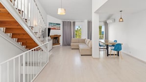 A spacious living area with a wooden staircase, a sofa, a dining table with chairs, and a view of the outdoors. - Holiday Home 'París' with Sea Views, Wi-Fi and Air Conditioning (Benalmádena)