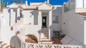 A white building with a tiled roof, a staircase, and a small garden area. - Holiday Home 'París' with Sea Views, Wi-Fi and Air Conditioning (Benalmádena)