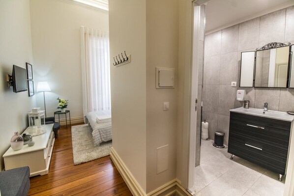 A modern bathroom with a dark vanity, a large mirror, and a shower area.