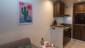 A compact living space with a kitchenette, a sofa, a cactus artwork, and a magazine on a small table. - Charming Riviera 2F - One Bedroom Apartment, Sleeps 4 (Antibes)