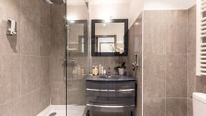 A modern bathroom with a glass-enclosed shower, a dark-toned sink, and a toilet. - One-bedroom Terrace 2B (Antibes)