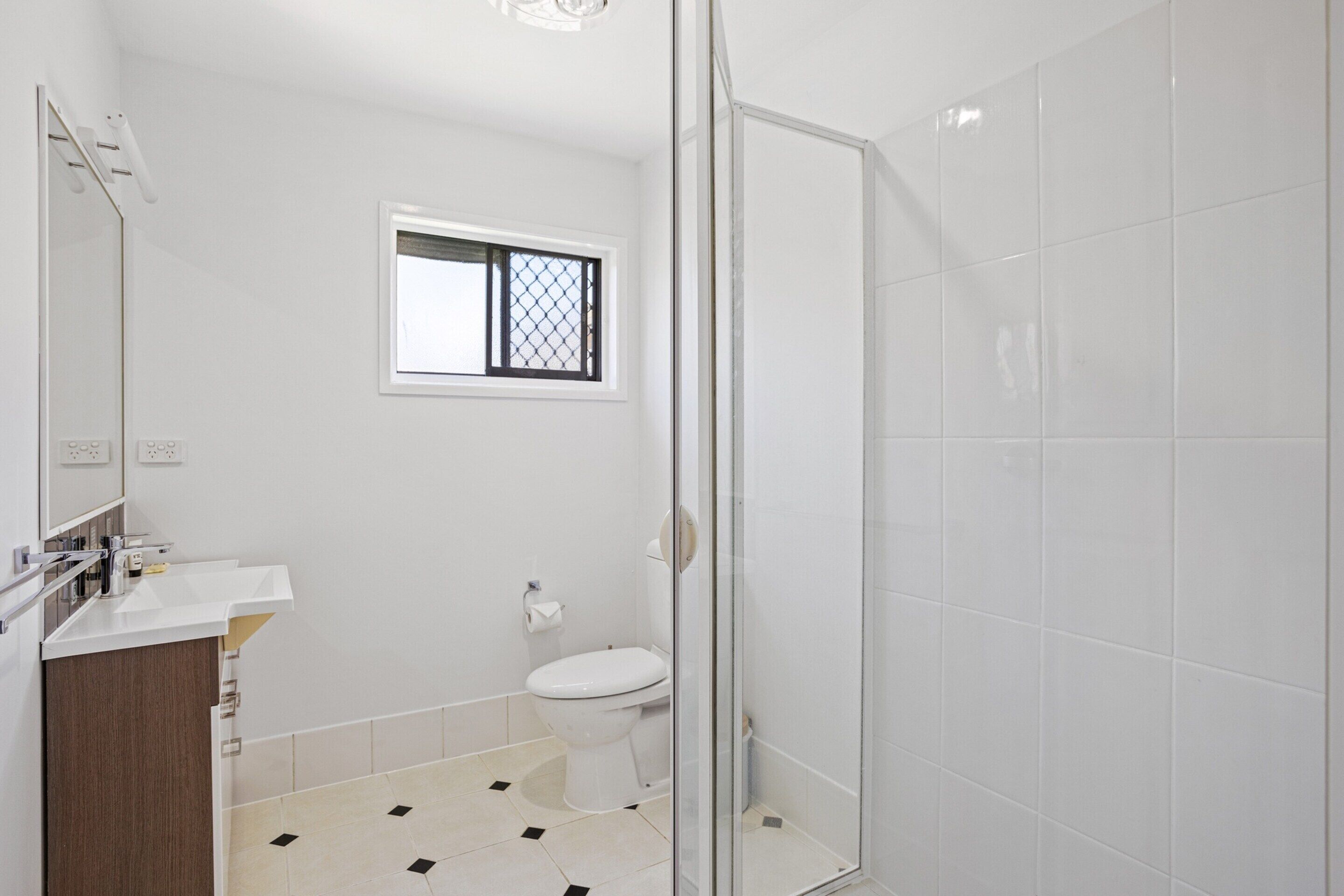 A bathroom with a toilet, sink, and a glass shower enclosure.