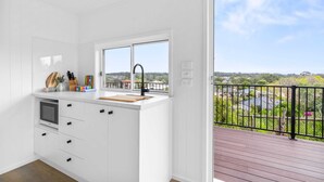 Eine moderne Küche mit weißen Schränken, einem eingebauten Backofen und einem Fenster mit Blick auf einen Balkon und die Umgebung.