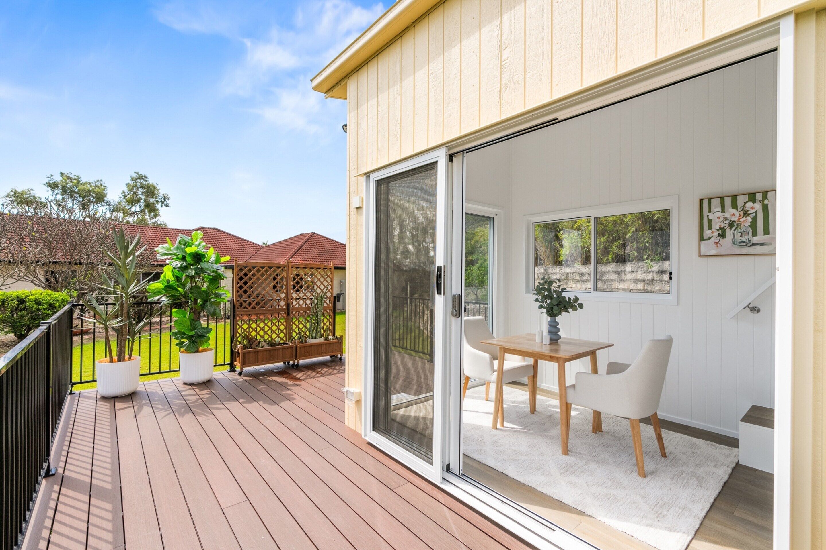 A deck with a sliding glass door leading to a patio with a table and chairs.