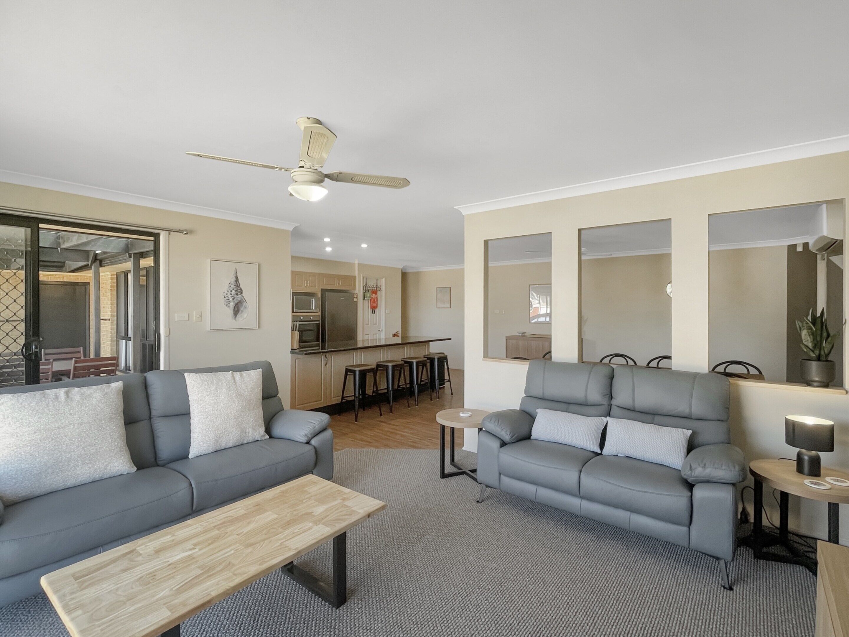 A modern living room with two grey sofas, a wooden coffee table, and a ceiling fan.