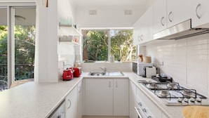 A modern kitchen with white cabinets, a stainless steel sink, and a gas stove.