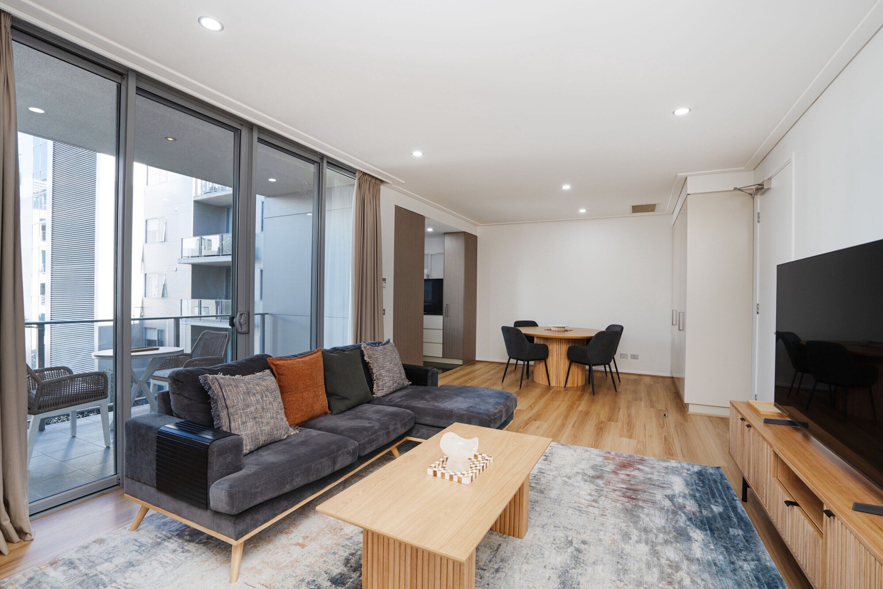 Una sala de estar moderna con un sofá gris, una mesa de centro de madera y un televisor de pantalla plana.