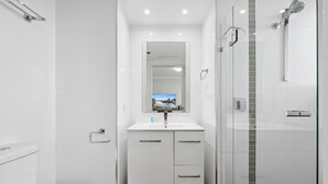 Ein modernes Badezimmer mit Toilette, Waschbecken mit Spiegel und einer Duschkabine.