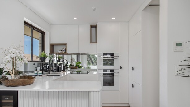 Una cocina moderna con armarios blancos, una isla central y electrodomésticos de acero inoxidable.