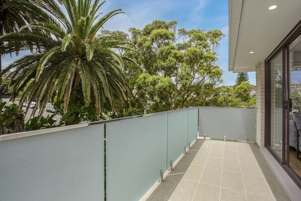 A balcony with a view of trees and a car. - North-east Facing Modern 2-bed Apartment (Sydney)
