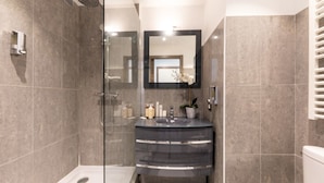 A modern bathroom with a glass-enclosed shower, a dark-toned sink, and a toilet. - One-bedroom Terrace 5B (Antibes)