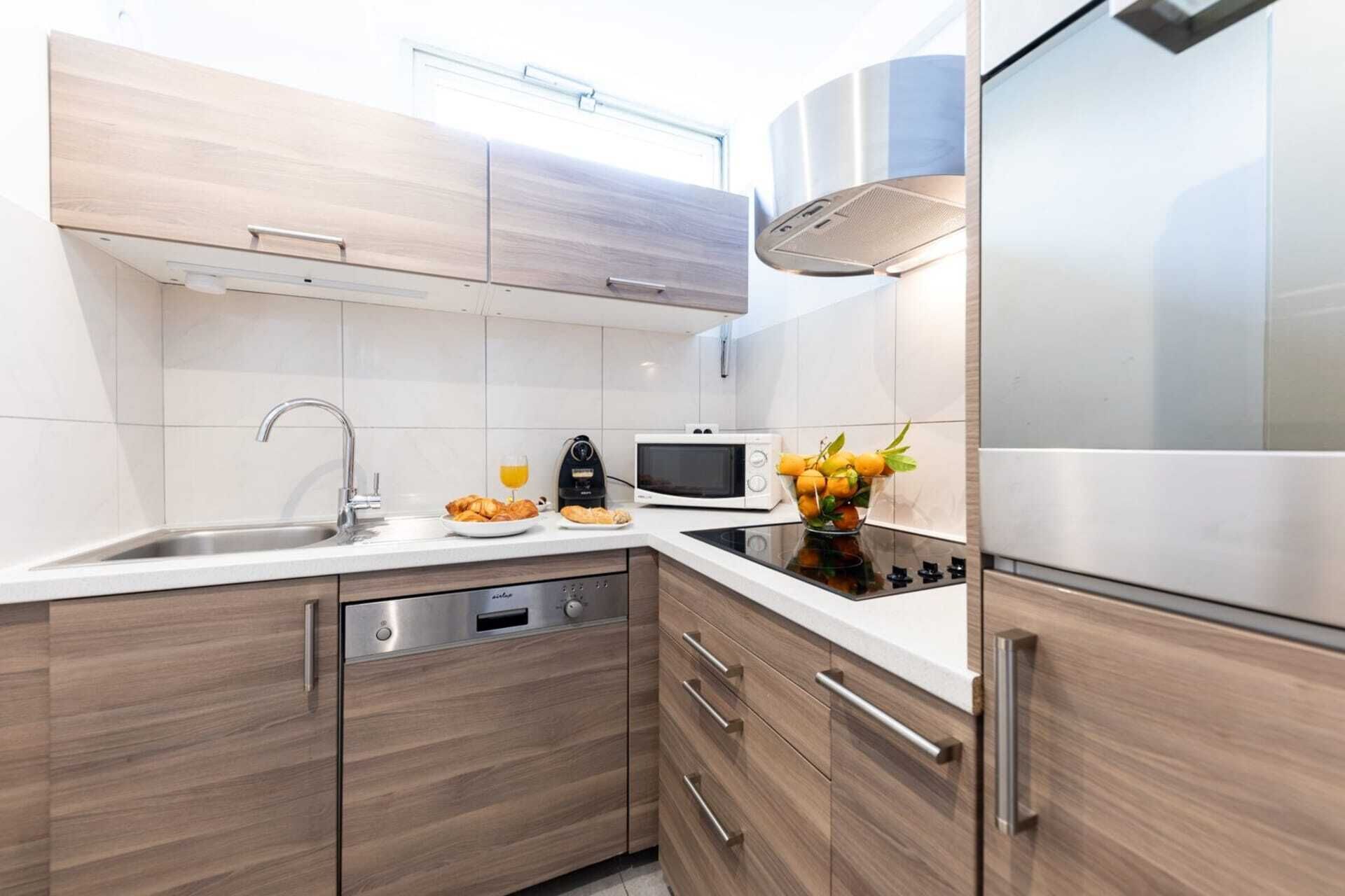 Une cuisine moderne équipée d’un lave-vaisselle, d’un four à micro-ondes, d’une cuisinière et d’appareils électroménagers en acier inoxydable.