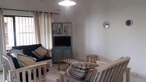 A living room with a sofa, a small table, and a TV. - CASA DEL SOL 4 a Stroll to the beach (Margate)