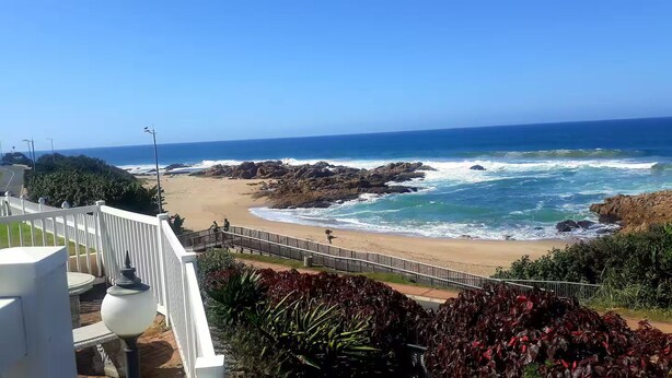 A beach view with a rocky shoreline, a wooden walkway, and a white railing. - CASA DEL SOL 4 a Stroll to the beach (Margate)