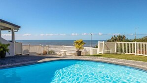 A swimming pool with a view of the ocean, surrounded by white fences and a small garden area. - CASA DEL SOL 4 a Stroll to the beach (Margate)