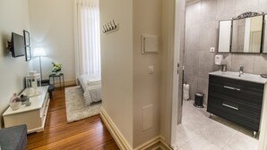 A modern bathroom with a dark vanity, a large mirror, and a shower area. - GuestReady - O Ateneu - Room 8 (Ponta Delgada)
