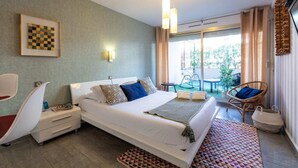 A hotel room with a bed, bedside tables, a chair, a small table, and a view of the outside. - Bright and Cosy 2 - Studio Apartment, Sleeps 2 (Antibes)