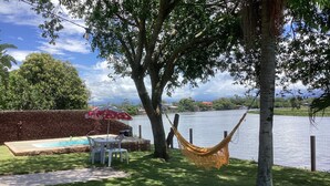 Un espace piscine équipé d’un hamac, de chaises et d’un parasol rouge.