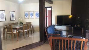 Un salon avec un canapé, une table à manger et des chaises, ainsi qu’un téléviseur.