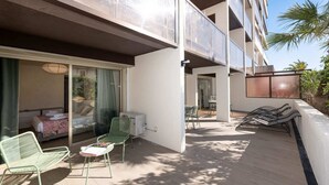 A hotel balcony with a bed, a table, chairs, and a fan. - Two-bedroom 1B - Two Bedroom Apartment, Sleeps 6 (Antibes)