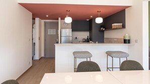 A compact kitchen with a refrigerator, a sink, and two bar stools. - Two-bedroom 1B - Two Bedroom Apartment, Sleeps 6 (Antibes)