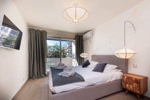 Ein modernes Schlafzimmer mit einem Bett, Nachttischlampen, einem Holznachttisch und Blick durch das Fenster.