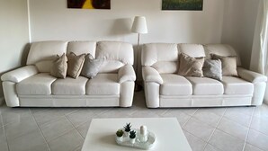 A living room with two white leather sofas, a white coffee table, and two wall-mounted air conditioners. - THE HOUSE OF CARLOTTA AND CAMILLA (Lazio)