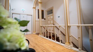 Una escalera con barandas blancas y escalones de madera, que conduce a un piso superior.