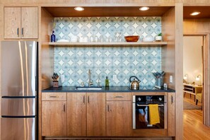 Una cocina moderna con armarios de madera, un refrigerador de acero inoxidable, un salpicadero con diseño y un horno empotrado.