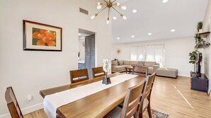 Ein modernes Wohnzimmer mit Essbereich, einer Sofagarnitur und einem Kronleuchter.