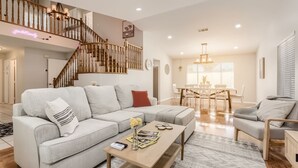 A spacious living room with a large sectional sofa, a wooden coffee table, and a staircase leading to an upper level. - Heated Pool with Cabana & GameRoom 15 Min to Strip (Las Vegas)