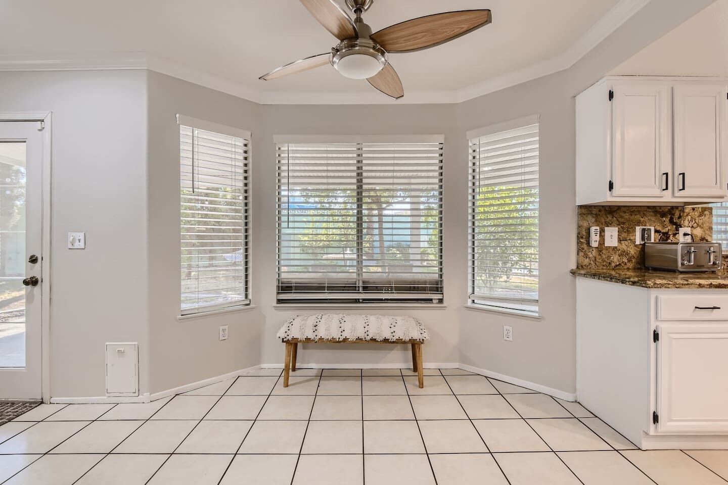A kitchen with white cabinets, a granite countertop, a built-in oven, and a ceiling fan.