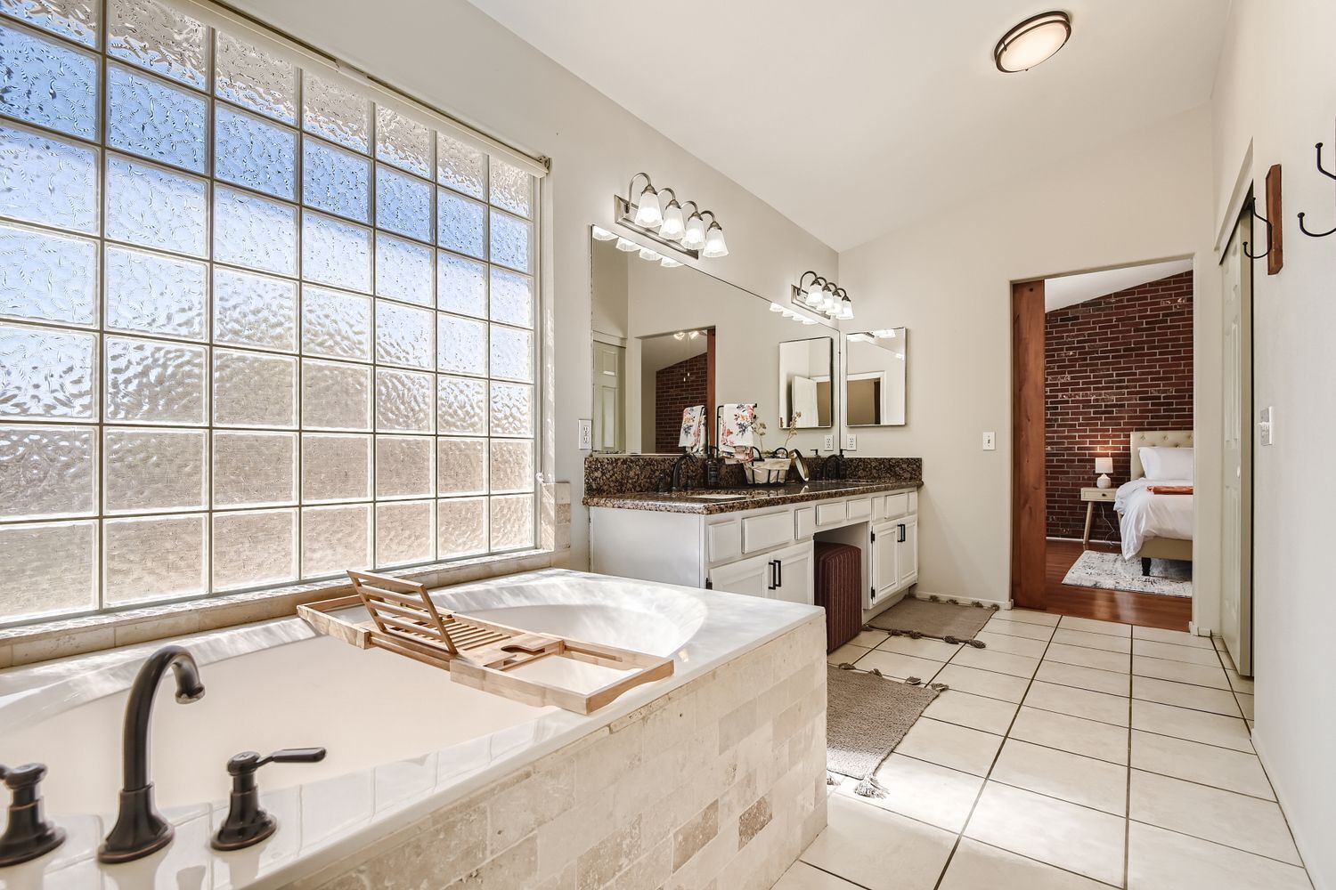 Une salle de bain dotée d’une grande fenêtre, d’une baignoire, d’un meuble-lavabo avec un miroir et d’un espace douche.