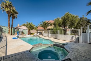 Une piscine avec un jacuzzi, des palmiers et un espace clÎturé.