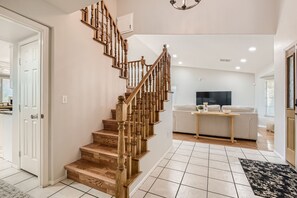 A staircase with wooden balusters, a flat-screen TV, a sofa, and a small table in a living area.