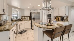 A modern kitchen with white cabinetry, stainless steel appliances, and a central island with bar stools. - Heated Pool with Cabana & GameRoom 15 Min to Strip (Las Vegas)