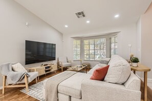 A spacious living room with a large flat-screen TV, a comfortable sofa, a wooden coffee table, and a TV stand with a flat-screen TV. - Heated Pool with Cabana & GameRoom 15 Min to Strip (Las Vegas)