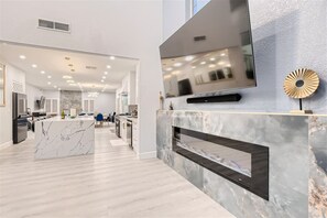 Una cucina moderna con piani in marmo, forno integrato e un grande televisore montato a parete.