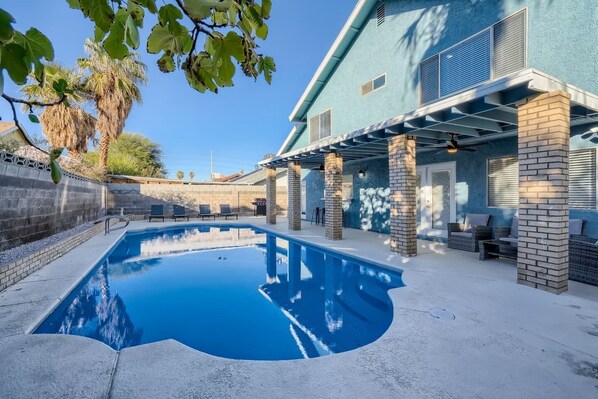 A swimming pool with lounge chairs and a covered patio area.