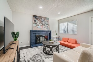 A living room with a fireplace, a flat-screen TV, a round coffee table, and a sofa.