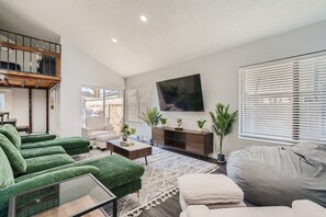 A modern living room with a sofa, coffee table, and a TV mounted on the wall.