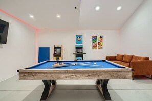 A pool table with a blue felt surface, surrounded by a white wall with a red LED strip.