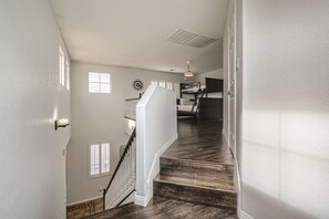 Un escalier avec des marches en bois, des murs blancs et une bouche dâaĂ©ration au plafond.