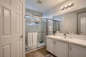 Une salle de bain avec une douche Ă parois de verre, un lavabo avec un miroir et un porte-serviettes.