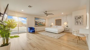 Een moderne slaapkamer met een groot bed, een plafondventilator en een stadsgezicht schilderij.