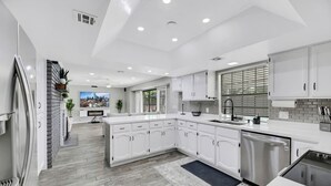 A modern kitchen with white cabinetry, a stainless steel refrigerator, and a large island.