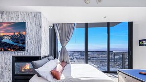 Una camera da letto moderna con vista sulla città, un camino e un letto grande.