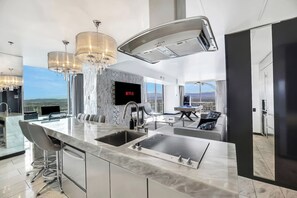 A modern kitchen with a large island, a flat-screen TV, and a pool table.